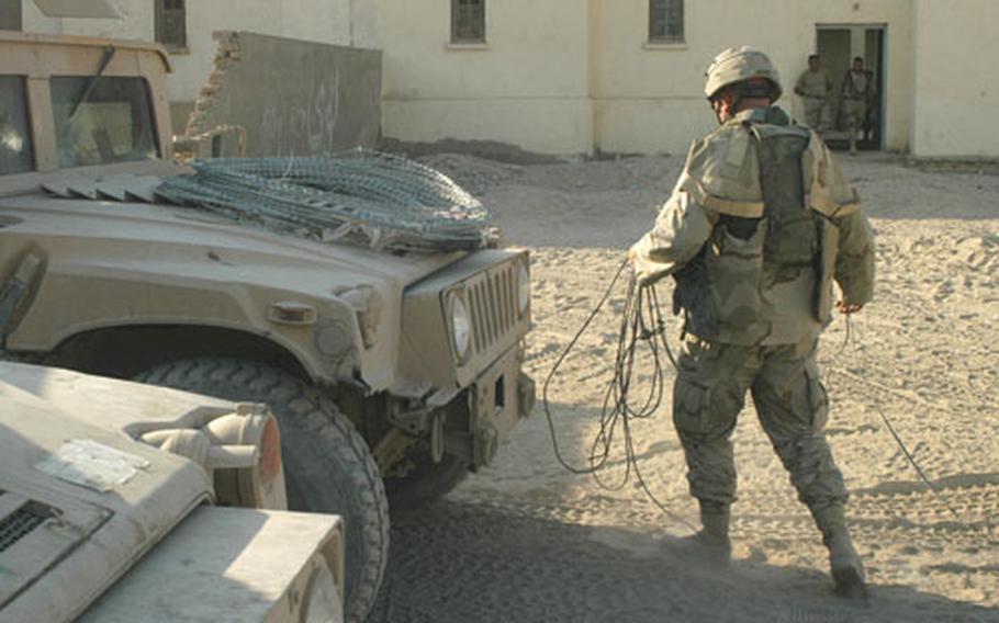 A soldier pulls electrical wire from the front of a Humvee after a mission in Najaf. Wire can hurt or kill gunners and wraps around the weaponry or some of the larger armored vehicles.