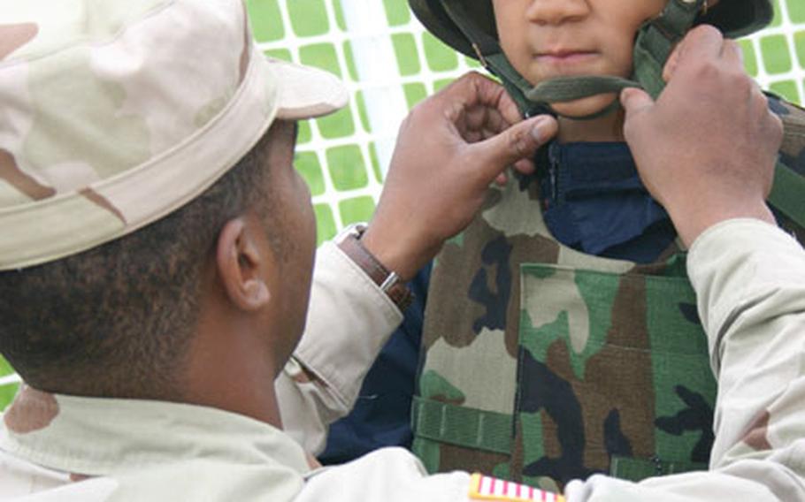The 1st Battalion, 7th Field Artillery Rear Detachment, held a Boys Day Out event at the shooting range in Schweinfurt on Monday. Second-grader Calvin Graham makes a face as Pvt. Erik Wright fastens his Kevlar helmet in preparation for his turn at the shooting range.
