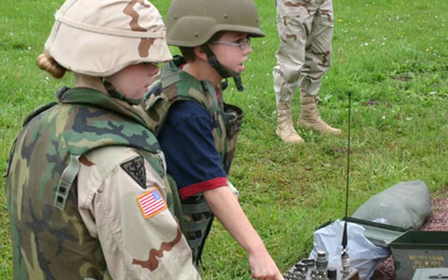 Spc. Julie Lamar watches as third-grader Joshua Zeeman pushes a button causing the target to raise after another boy shot it. Lamar, a medic from the 299th Forward Support Battalion, was there to ensure the safety of the children. Capt. Matthew Lennox, the 1st Battalion, 7th Field Artillery rear detachment commander, supervises.