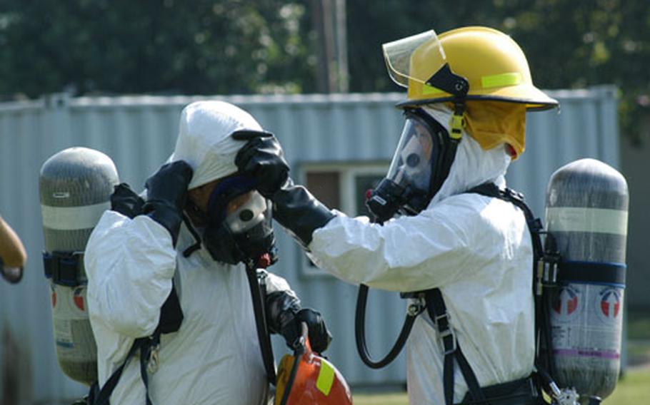 Camp Walker firefighters check each other&#39;s equipment before responding to a simulated biological attack at nearby Camp George in July.