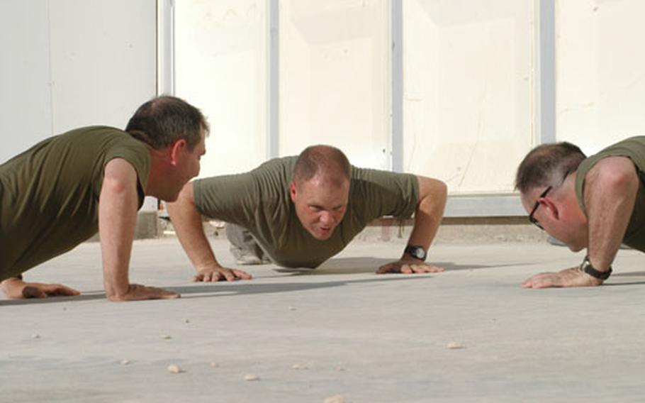 Navy chief petty officer selectees, from left, Jeff Cavallo, Roger Teel and Billy Hammond do push-ups Monday as part of their initiation process. The three sailors are assigned to the 11th Marine Expeditionary Unit at Camp Duke, Iraq.