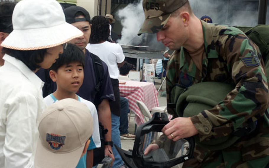 Staff Sgt. Justin Surran, 35th Civil Engineer Squadron, Misawa Air base, Japan, shows a Japanese family a uniform used to detonate explosive ordnance during Airfest 2004.