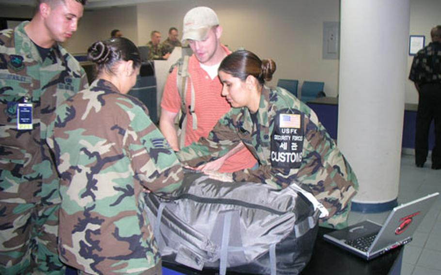 Customs airmen inside passenger terminal at Osan Air Base in South Korea go through baggage of just-arrived servicemember Thursday morning. The airmen, members of Osan&#39;s 51st Security Forces Squadron, are part of a team that works to prevent outlawed items from getting into South Korea. At right is Staff Sgt. Lisa Rodriguez, the team&#39;s noncomissioned officer-in-charge; center is Senior Airman Cristina Chomina, a customs inspector; left is Senior Airman Anthony Stanley, customs inspector in training.