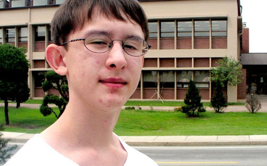 Nathan Carswell, 13, stands across the street from Osan American High School at Osan Air Base in South Korea. Nathan and his parents are anxiously awaiting Sept. 13, when school officials will tell them whether any vacancies have opened up.