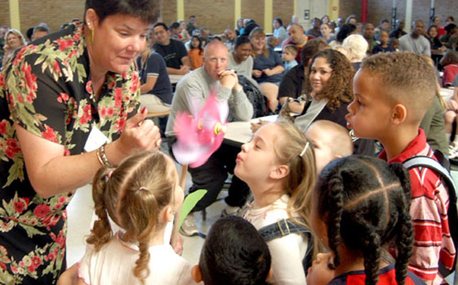 Kindergarten pupils blow on a pinwheel — signifying the winds of change — held by principal Shawne Cryderman at an assembly with parents before the first day of school at Mannheim Elementary.
