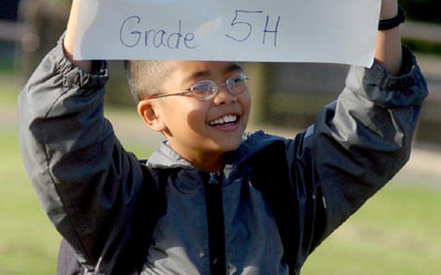 Andrew Luong, a fifth-grader at Alconbury Elementary School, RAF Alconbury, England, holds a sign telling his classmates where to congregate before the school&#39;s first day of classes on Tuesday.