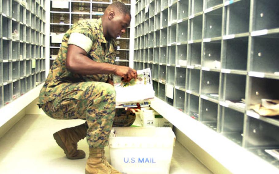 Lance Cpl. Deon Scott, postal clerk, sorts through magazines and catalogs before placing them in mailboxes in the new Camp Foster Post Office.