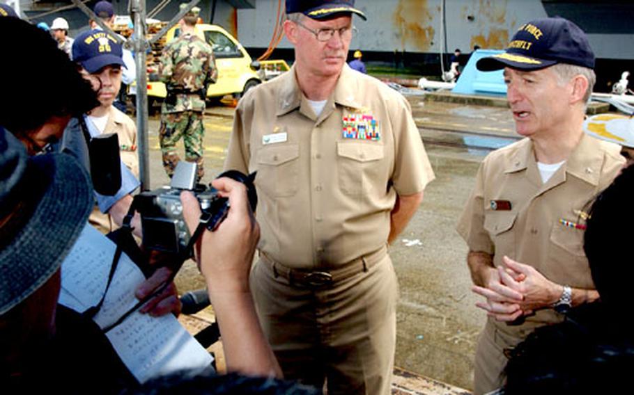 Rear Adm. James D. Kelly, right, commander of the Kitty Hawk Strike Group, stands with Capt. Thomas A. Parker, USS Kitty Hawk commanding officer, as they conduct an interview with local Japanese media.