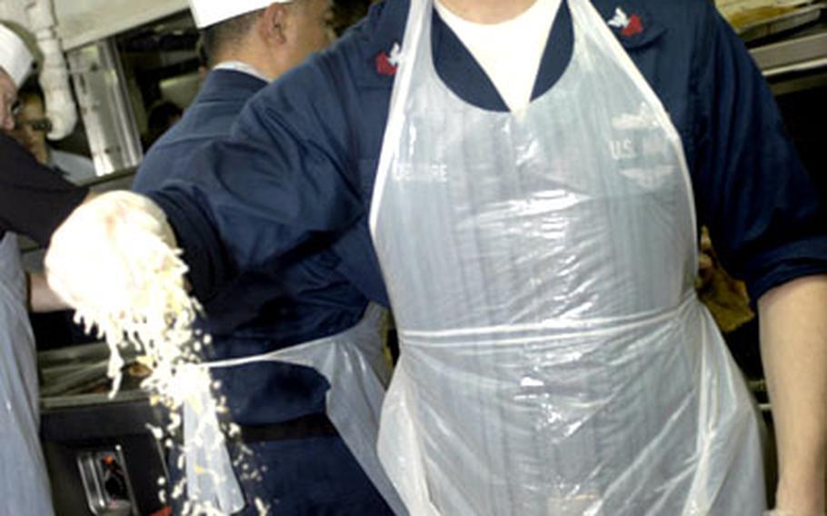 Petty Officer 1st Class Ryan Delcore of Greensville, Texas, spreads toppings onto a pizza Monday during the final night of USS Kitty Hawk’s just-ended underway period. Petty officers first class treated fellow sailors to pizza.