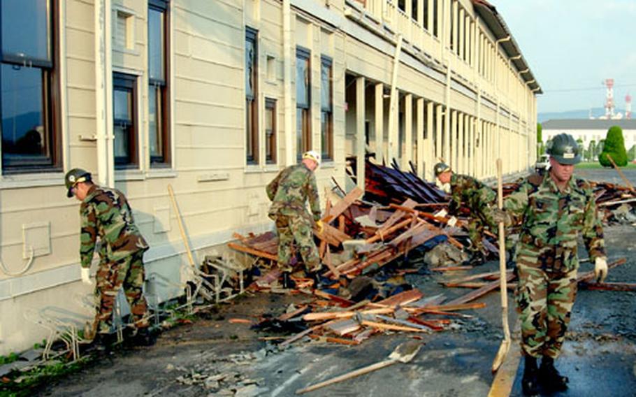 Servicemembers collect debris Wednesday following Typhoon Songda, which blew off about half of the roof at Iwakuni Marine Corps Air Station&#39;s Logistics Building the night before.