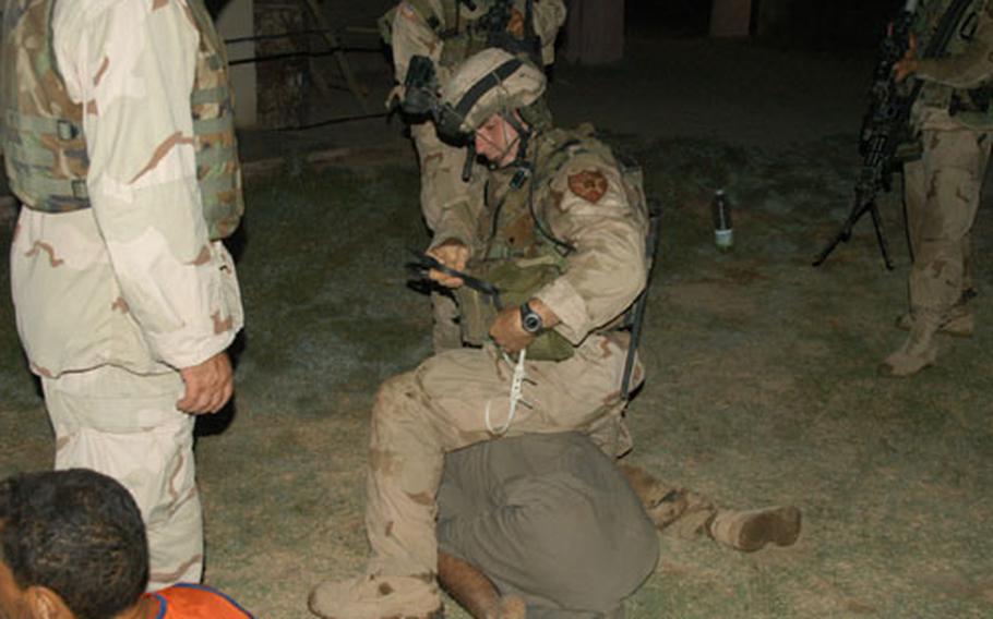 A soldier from Company C, 1st Battalion, 506th Infantry Regiment zipper cuffs an Iraqi man who resisted soldiers during house raids in Abu Fleis, Iraq, on Sunday. The man was later released.
