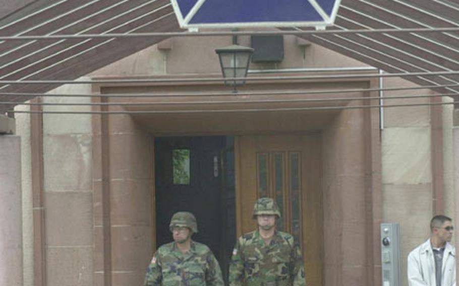 Lt. Gen. Ricardo Sanchez, left, and Command Sgt. Maj. Michael Bush wait under the awning of the V Corps headquarters as troops prepare to welcome Bush as corps&#39; top enlisted soldier during a ceremony Monday.