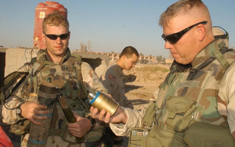 Staff Sgt. William McInnis, left, and 1st Sgt. Keith Adams of Company D, 1st Battalion, 503rd Infantry Regiment, examine a cache of explosives seized in Ramadi, Iraq, on Thursday.