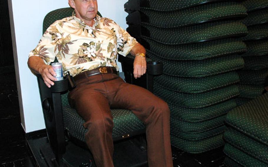 Frank DeSilva, public affairs specialist for Sasebo Naval Base&#39;s Morale, Welfare and Recreation department, tries out one of the new theater chairs being installed at the Showboat Theater. The 319 hunter green chairs are wider, better cushioned and equipped with drink holders.