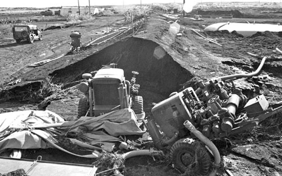 The ruptured fuel bladder and wrecked machinery lay strewn in a break in the fuel storage embankment at Camp Fuji after the fire.