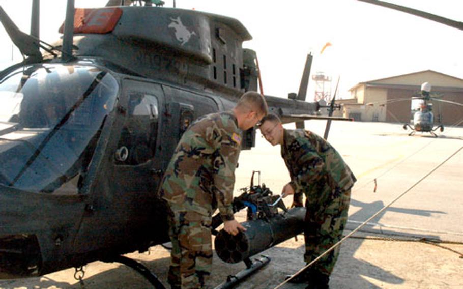 Spc. Brett Pierce, left, and Pfc. Richard Elder of 4th Squadron, 7th Cavalry Regiment work on a Kiowa Warrior helicopter at Camp Stanton, South Korea, on Tuesday.