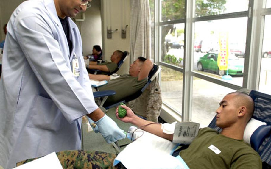 Marine Pfc. Ser Thao from 3rd Materiel Readiness Battalion watches as the Armed Services Blood Bank Center&#39;s Air Force Staff Sgt. Frank Lobos begins to draw blood from his arm. Thao and fellow servicemembers donated an ASBBC Okinawa record of 180 pints of blood Thursday during 3rd MRB&#39;s drive on Camp Kinser, Okinawa.