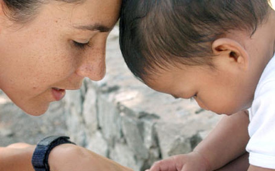 Tech Sgt. Rebecca Carlson, of the 353rd Operations Support Squadron, plays with eight-month-old Joshua Dunai at a children&#39;s shelter in Chonburi, Thailand. Carlson was among a dozen members of the 353rd Special Operations Group from Kadena Air Base who volunteered to visit the shelter and distribute food and other items to needy families during a break in a month-long training exercise with the Thai military.