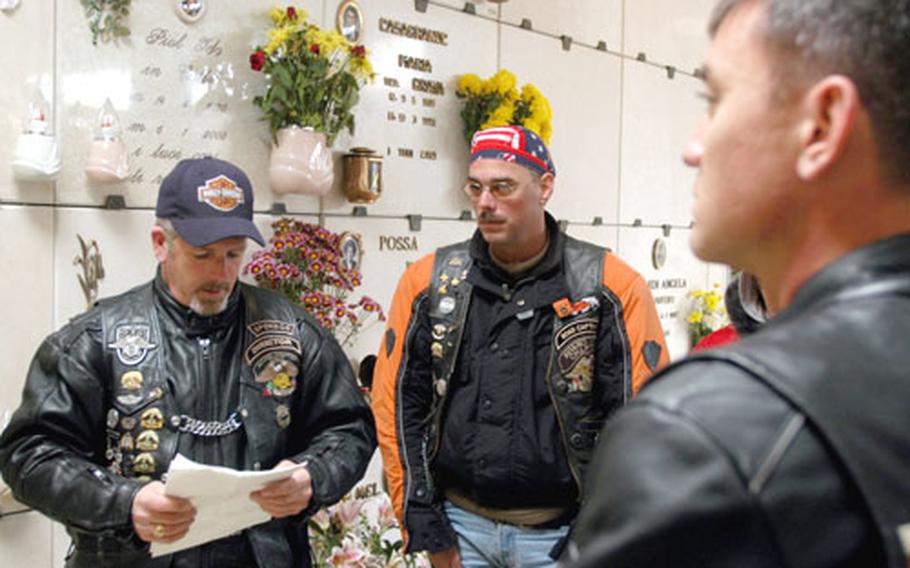 Wayne Parks, left, reads a tribute to veterans while Jeff Jamison, center and Rob Hood look on at the gravesite of a former servicemember in Revine Lago, Italy. A group of motorcyclists from Aviano, Italy, traveled 25 miles to pay him tribute on Veterans Day.