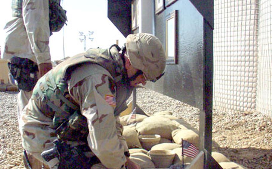 First Sgt. Brent Jurgersen plants a little American flag beneath a memorial to seven 1st Squadron, 4th Cavalry Regiment soldiers and one civilian killed this year from Forward Operating Base MacKenzie, Iraq, the squadron’s headquarters base. The memorial was erected Tuesday in front of the base’s new chow hall, which opened in time for a noon visit by 1st Infantry Division commander Maj. Gen. John Batiste. The new wooden chow hall replaces two tents, which burned to the ground about six weeks ago.