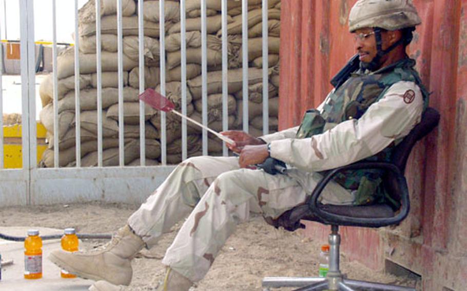 Sgt. Lamar Waring, 24, of the 1st Battalion, 113th Field Artillery from the North Carolina National Guard, watches a gate at Forward Operating Base Wilson, Iraq, with two weapons ready: his rifle and his fly swatter.