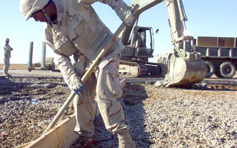 Spc. Rico Williams, 25, of the Ohio National Guard&#39;s 216th Engineer Battalion, rakes gravel in a bomb crater under repair at the Camp Speicher airfield in Tikrit, Iraq, while a steam shovel digs nearby.