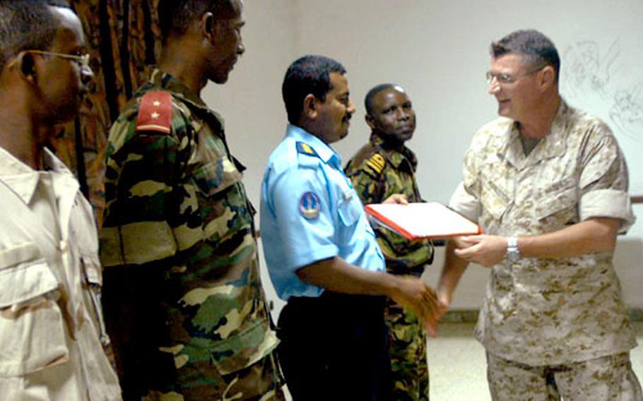 Marine Col. Craig S. Huddleston, right, chief of staff for Combined Joint Task Force-Horn of Africa, presents certificates recently to African troops who completed a program to help their countries work together to fight terrorism. The presentation took place at Camp Lemonier, Djibouti.