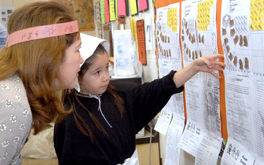 Dressed as a Pilgrim, Kelsey Barbosa, 8, a third-grader at Argonner Elementary School in Hanau, Germany, shows her mom, Ramona, a class project on the Pilgrims.