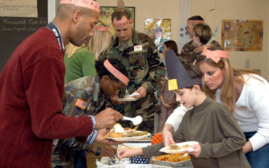 American Indians and Pilgrims, actually Old Argonner Elementary School third-graders and parents, dish up their food as they celebrate Thanksgiving Wednesday at the Hanau, Germany, school.