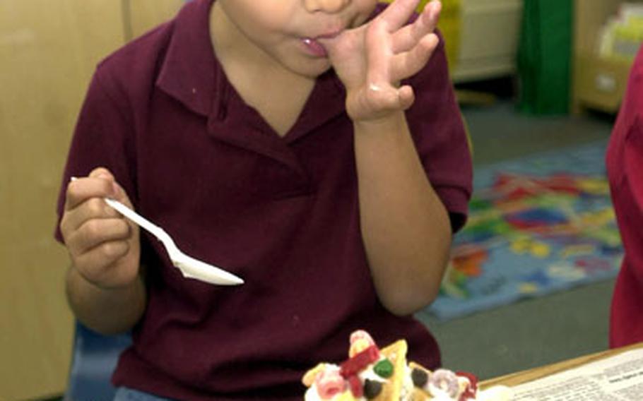 Zukeran Elementary School first-grader Rodney Villarreal samples the "glue," actually icing, he and his classmates used to make gingerbread houses Tuesday at Camp Foster, Okinawa.