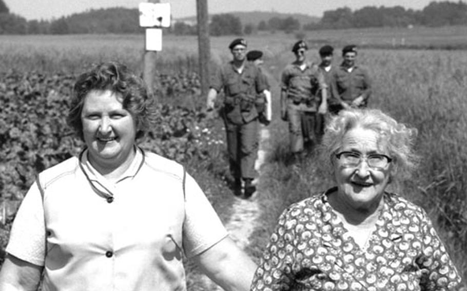 Soldiers on a routine patrol at the border between West Germany and Czechoslovakia share the path with a pair of local residents out for a stroll.