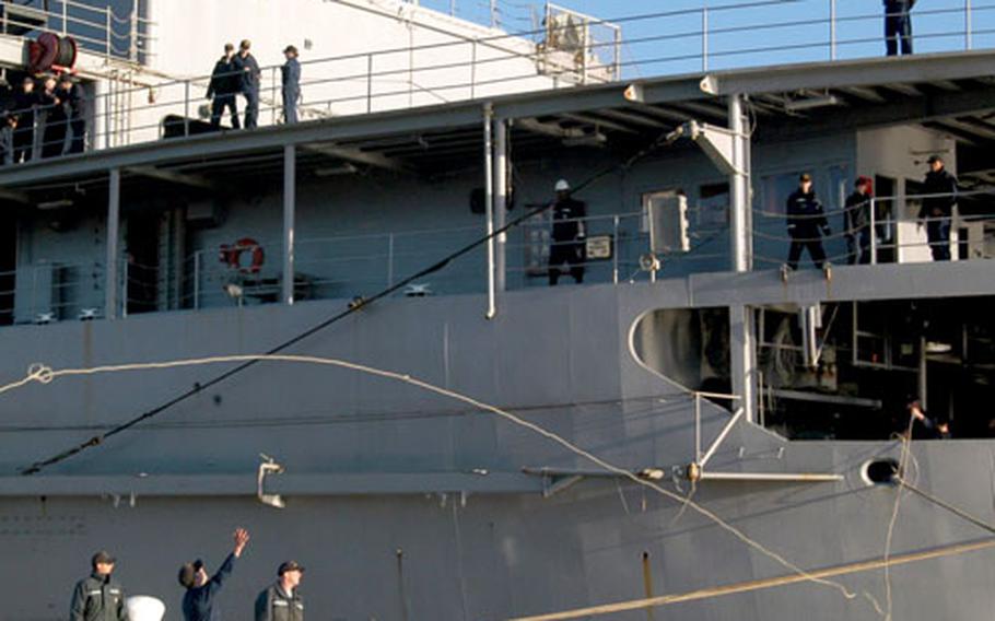 Line handlers on Pier 1 at Naval Station Rota, Spain, grab for a rope thrown from the USS Emory S. Land.