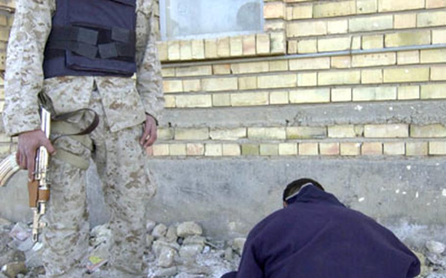 A member of the Iraqi National Guard watches over a young man detained by a joint patrol of U.S. and Iraqi forces Thursday near the city of Ramadi, Iraq.