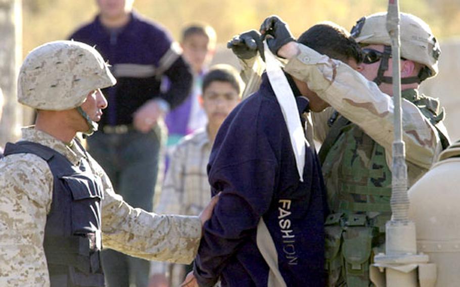 U.S. and Iraqi forces detain a man Thursday during a joint patrol of neighborhoods on the outskirts of Ramadi, Iraq. After a search of his house, the man was taken to a detention facility on a U.S. base.