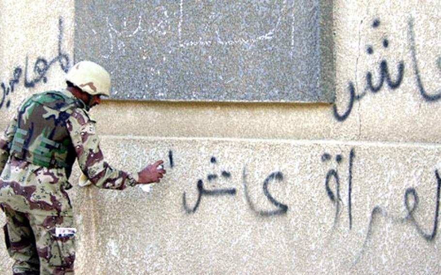 An Iraqi National Guard soldier spray paints, "Iraq is good, elections are good," over what an interpreter said was pro-insurgent graffiti.