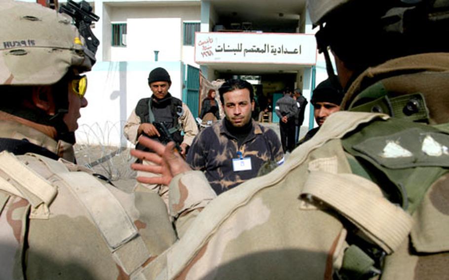 First Lt. Daniel Hurd, left, and Sgt. 1st Class James Shinholt talk to election officials and Iraqi police officers Sunday at a polling site in Baghdad.