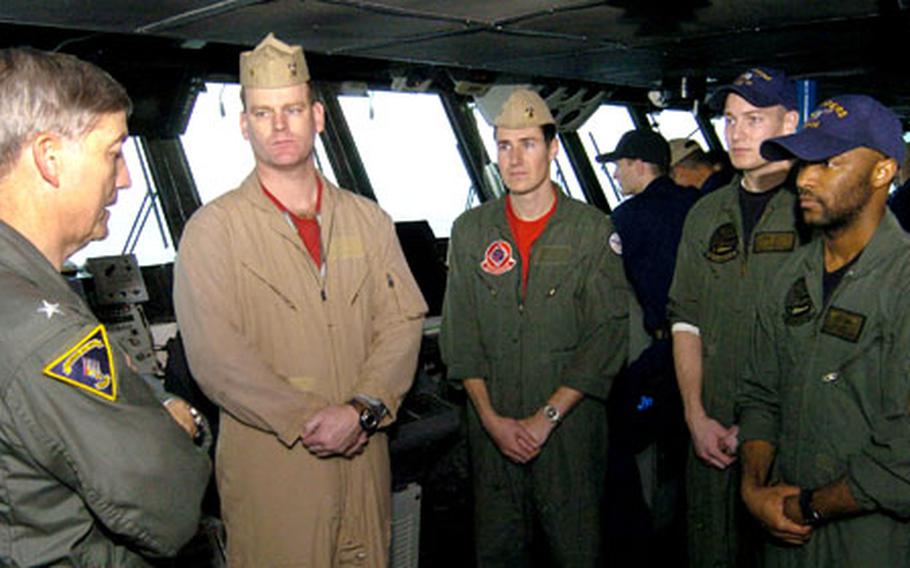 Rear Adm. James D. Kelly, far left, commander of Carrier Strike Group 5, congratulates aviation warfare systems operators Petty Officers 2nd Class Bennie Romiti, second from right, and Jerard Cook, far right, on Sunday for their rescue of Lt. Cmdr. Markus Gudmundsson and Lt. j.g. Jon Vanbragt of Strike Fighter Squadron 102 Saturday night.