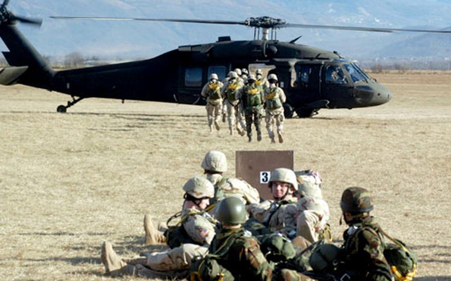 As another group waits its turn, soldiers from the 2nd Battalion, 503rd Infantry Regiment hurry toward a Black Hawk helicopter bound for the Juliet drop zone near Aviano Air Base, Italy, on Wednesday. The helicopter, assigned to Company B, 5th Battalion, 158th Aviation Regiment, stayed busy all day by making dozens of drops.