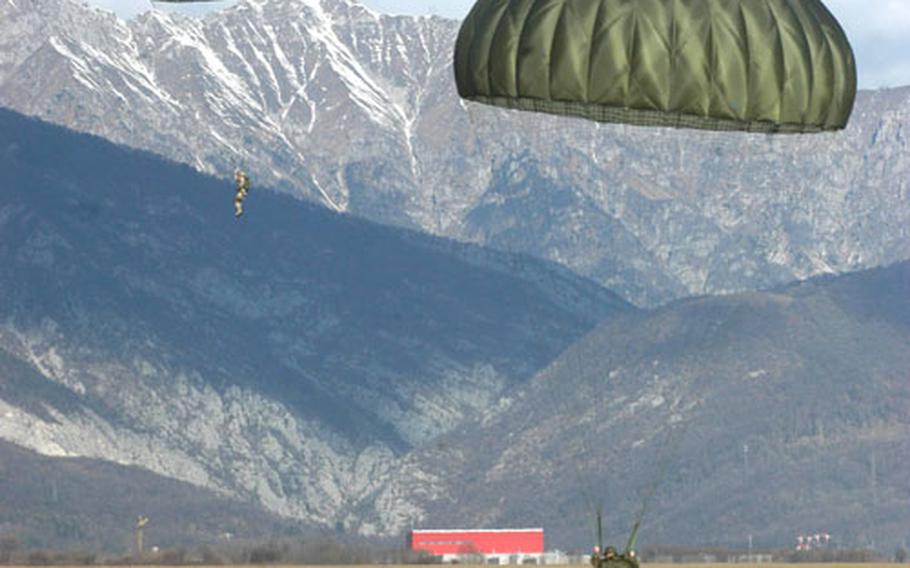 An Italian paratrooper touches down Wednesday at the Juliet drop zone while an American counterpart drifts down with the Dolomite mountain range in the background. Soldiers had clear skies and a small breeze — perfect weather for jumping.