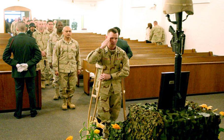 Sgt. William Rigby, Headquarters and Headquarters Troop, 1st Squadron, 4th Cavalry, who was recently injured in combat, pays his last respects to his fallen comrade and friend, Sgt. William Kinzer, at a memorial service Wednesday at Ledward Barracks in Schweinfurt, Germany.