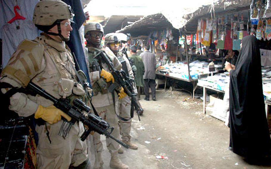 Soldiers from Company A, 1st Battalion, 509th Parachute Infantry Regiment stop during a patrol through Abu Ghraib’s market recently. They are, from left, Sgt. Joel Fredrickson, 1st Lt. Omar Minott, Spc. Luis Chavira and Cpl. Christopher Culler. The unit’s members, who are fighting insurgents in the town, play insurgents themselves when they’re back at their home base of Fort Polk, La.