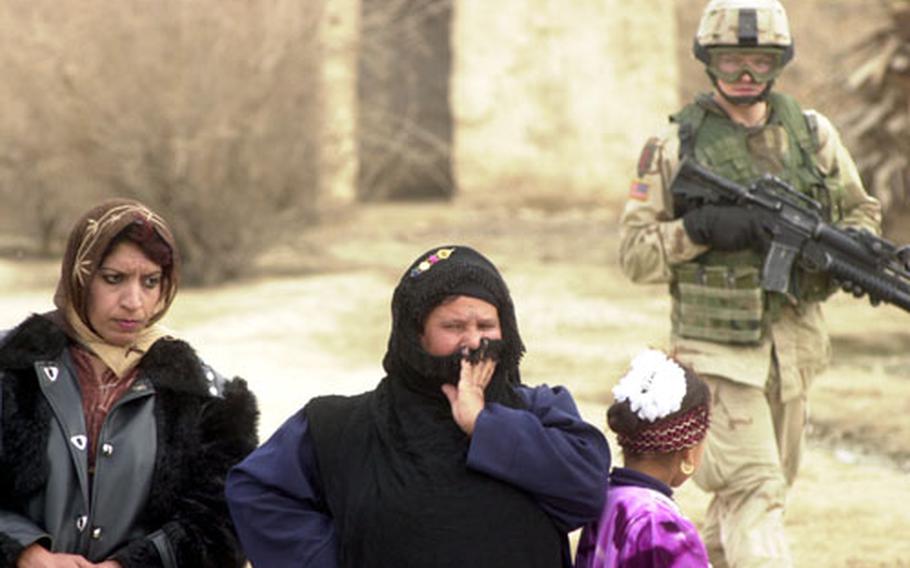 Iraqi women appear tense as they wait for Pfc. Matthew Oberloh, background, and other 1st Infantry Division soldiers to finish searching their home in a tiny village north of Tikrit.