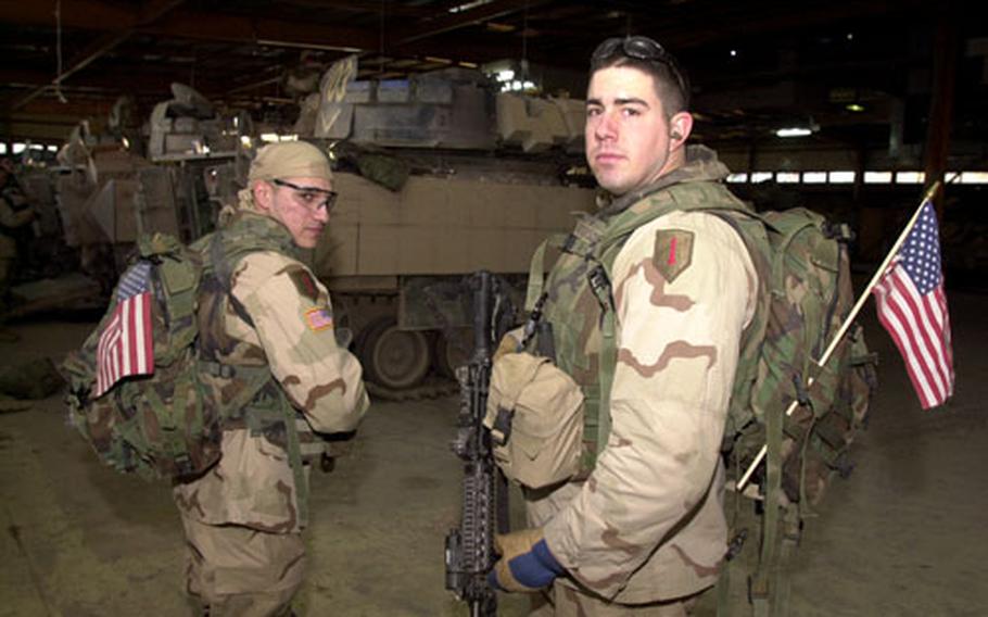 Spc. Justin Patterson, left, and Spc. Javier Aguilar prepare to get in the Bradley fighting vehicles that will take them to Ad-Dawr.
