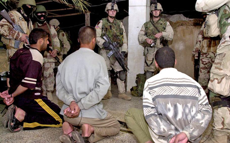 American and Iraqi soldiers wait for Iraqi forces to pick up three men suspected of building improvised bombs in Ad-Dawr.