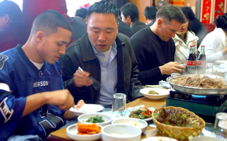 Pvt. Gary Beniquez, left, and Pvt. Ryan Bueger taste Korean food at a restaurant in Uijongbu. At last month’s newcomers briefing, Beniquez, 18, learned about activities he can take part in during his South Korea tour.