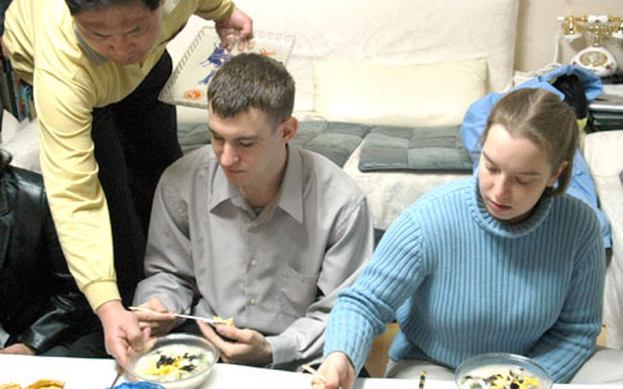 Shin Ho-gyun, left, serves rice cake and dumpling soup Wednesday to Spc. Christopher Tait, 20, of San Diego, and Sgt. Samantha Aston, 23, of Mercersbury, Pa. Shin invited a group of 8th Army soldiers to his Seoul home to celebrate the Lunar New Year.
