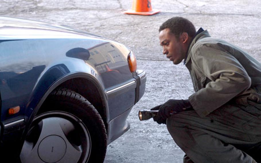 Staff Sgt. Clive Clarke looks at a tire during an inspection by the 31st Logistics Readiness Squadron. Vehicle owners on base were invited to the inspection to see if their tires had been damaged by security devices installed at the gates of Aviano Air Base, Italy.