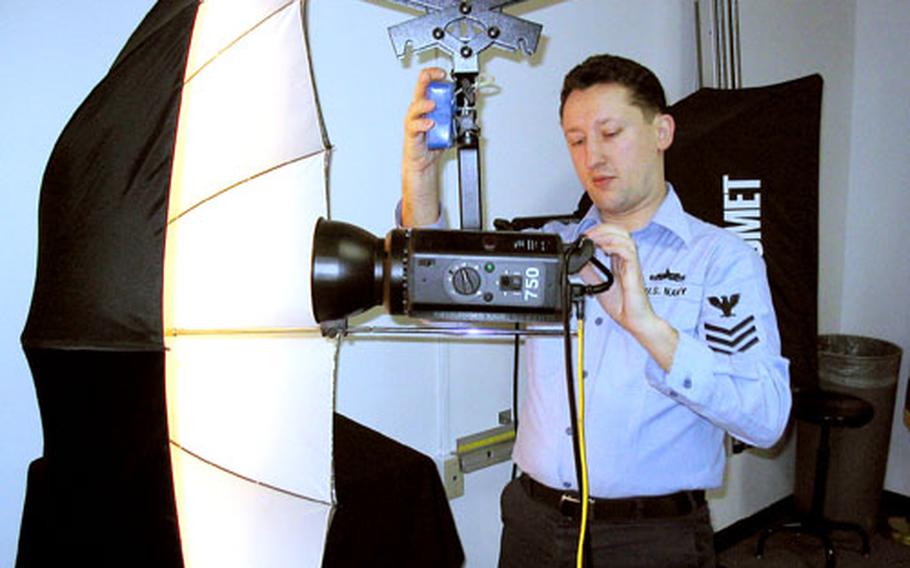 Navy photographer Petty Officer 1st Class Josh Phelps, leading petty officer at Fleet Imaging Facility Pacific, Sasebo Naval Base, adjusts a studio light he and his staff use to photograph portraits.