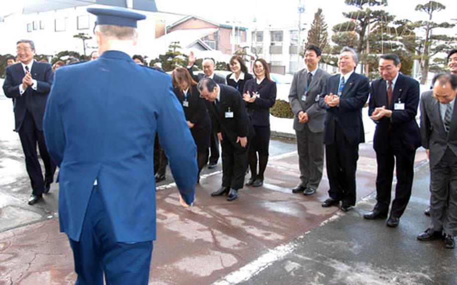 Misawa City Mayor Shigeyoshi Suzuki, far left, and his staff wave, bow and clap as U.S. Forces Japan Commander Lt. Gen Bruce A. Wright departs the mayor&#39;s office Monday.