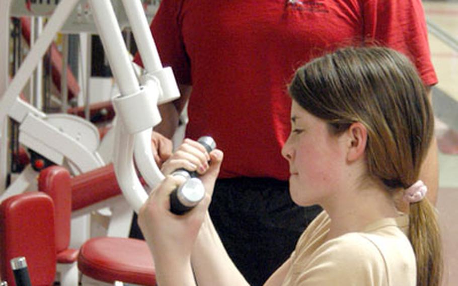 Instructor Eddie Bonilla watches Annan Morelli exercise on a Nautilus machine.